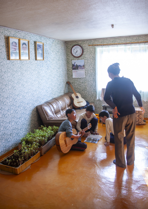 Family with twins in front of the portraits of the Leaders, North Hamgyong, Jung Pyong Ri, North Korea