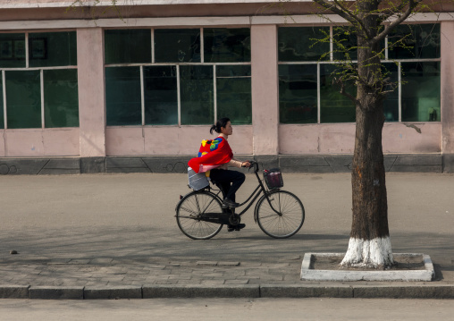 North korean woman with her babay in the back riding a bicycle, Kangwon-do, Wonsan, North Korea