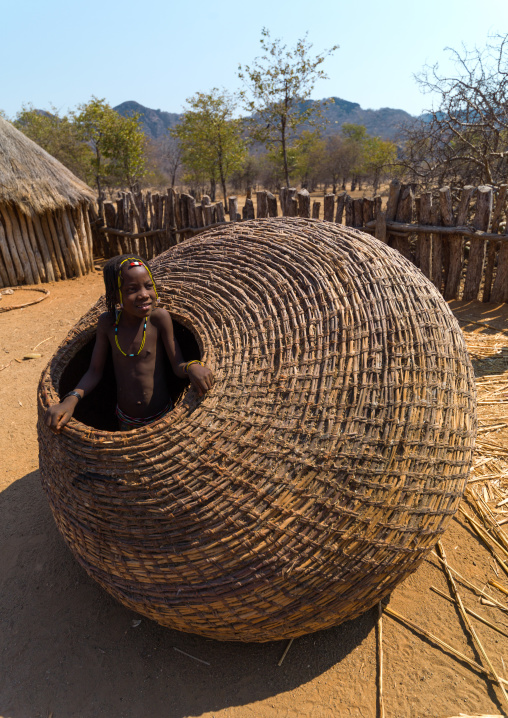 Muhacaona tribe girl inside a giant basket used to keep the corn, Cunene Province, Oncocua, Angola