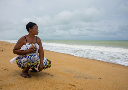 Benin, West Africa, Ouidah, mrs kpsouayo carrying the carved wooden figures made to house the soul of her dead twins on the beach