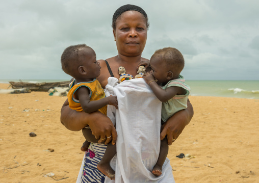 Benin, West Africa, Ouidah, mrs kpsouayo carrying the statues of her dead twins and her two boys twins