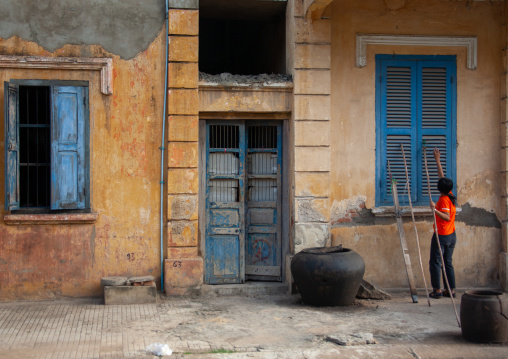 Cambodian woman closing the windows of an old colonial house, Battambang province, Battambang, Cambodia