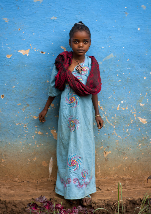 Young ari girl in a beautiful dress poses in front of a house in jinka omo valley Ethiopia