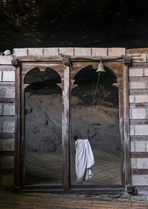 Priest Ringing The Bell Inside Yemrehana Krestos Rock Church, Lalibela, Ethiopia