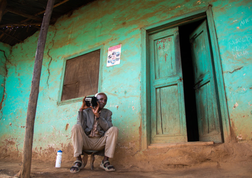 Old muslim man listening to the radio in front of his house, Omo valley, Jinka, Ethiopia