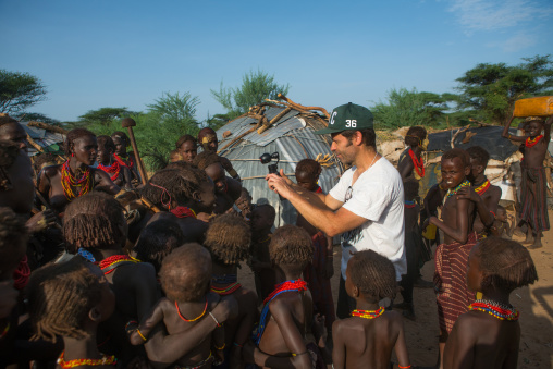 European tourist showing the screen of his camera to children in dassanech tribe, Omo valley, Omorate, Ethiopia