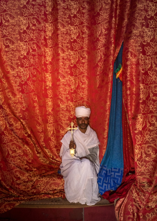 Ethiopian orthodox priest holding a cross inside a rock church, Amhara region, Lalibela, Ethiopia