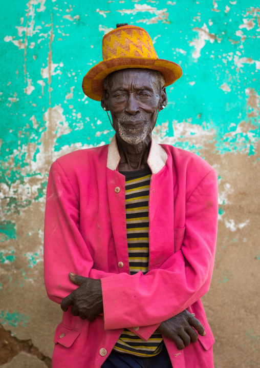 Portrait of an old Hamer tribe man with a yellow hat and a pink jacket, Omo valley, Turmi, Ethiopia
