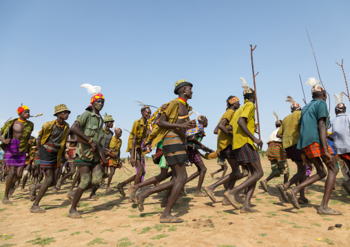 Men running in line with weapons during the proud ox ceremony in the Dassanech tribe, Turkana County, Omorate, Ethiopia
