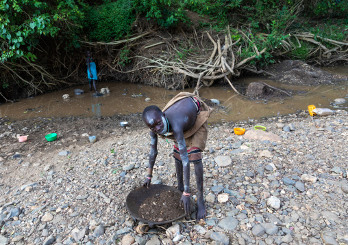 Suri tribe girl doing gold panning in a river, Omo valley, Kibish, Ethiopia