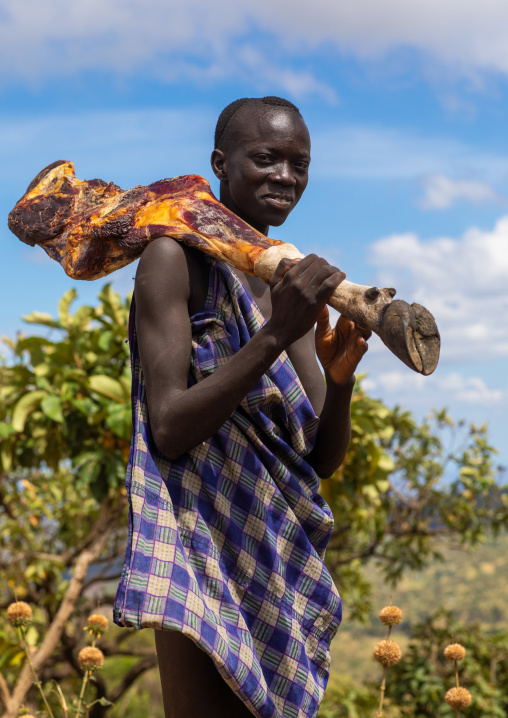 Suri man carrying meat on his shoulder, Omo valley, Kibish, Ethiopia