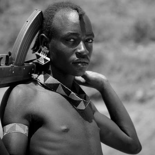Black And White Portrait Of A Banna Tribe Warrior With Kalashnikov, Omo Valley, Ethiopia
