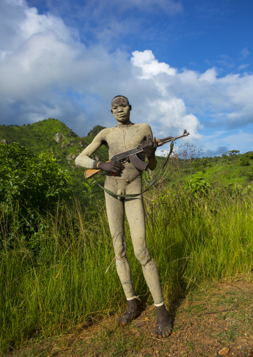 Suri tribe man with body paintings posing with a kalashnikov, Omo valley, Ethiopia