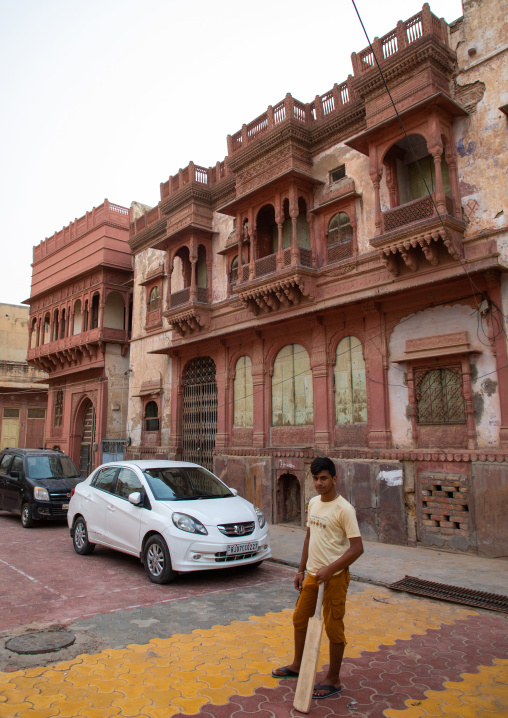 Indian young man playing cricket in front of a haveli in the old city, Rajasthan, Bikaner, India