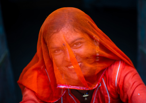 Portrait of a rajasthani woman hidding her face under a orange sari, Rajasthan, Jaisalmer, India