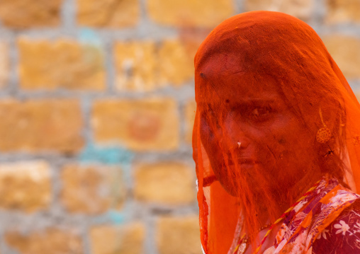 Portrait of a rajasthani woman hidding her face under an orange sari, Rajasthan, Jaisalmer, India