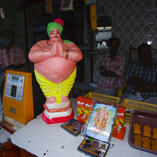 Men Sitting In The Shadows Behind A Stall Selling Fruit Juice And Religious Trinkets, Trichy, India