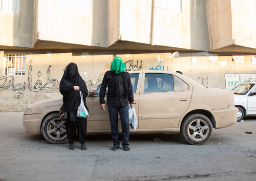 Shiite couple with veiled face in front of a car covered with mud decorated for Ashura  commemoration, Lorestan Province, Khorramabad, Iran