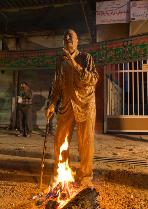 Iranian shiite muslim man standing in front of a bonfire after rubbing mud on his body during the Kharrah Mali ritual to mark the Ashura ceremony, Lorestan Province, Khorramabad, Iran