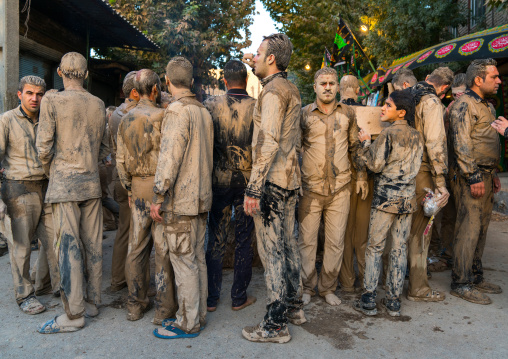 Iranian shiite muslim men gather around a bonfire after rubbing mud on their clothes during the Kharrah Mali ritual to mark the Ashura day, Lorestan Province, Khorramabad, Iran