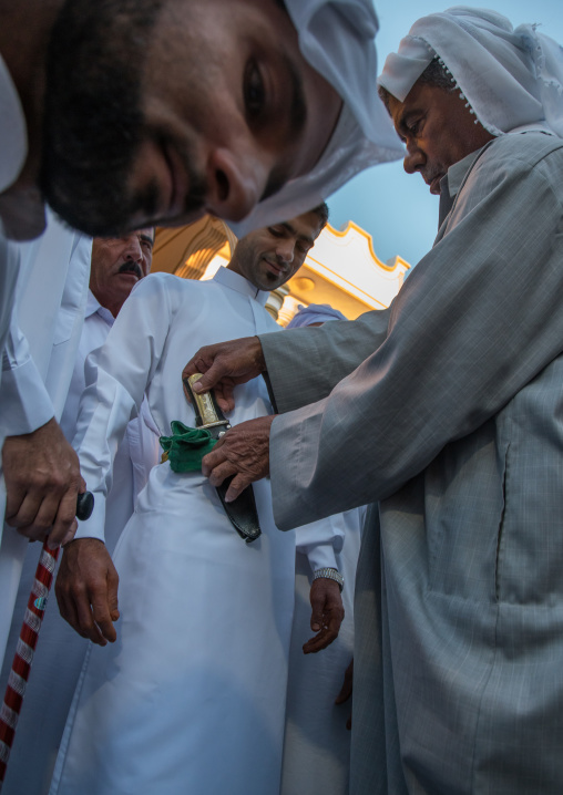 groom changing his clothes to wear new ones and a knife during the wedding ceremony, Hormozgan, Bandar-e Kong, Iran