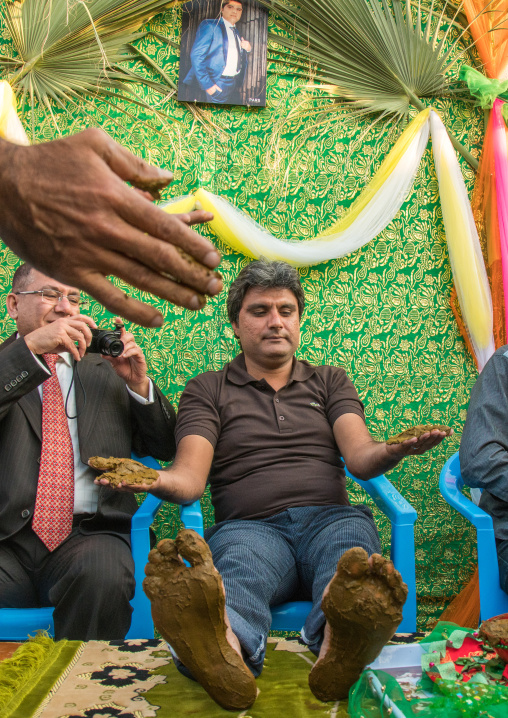 groom hands and feet being covered with henna during his wedding ceremony, Hormozgan, Kushkenar, Iran