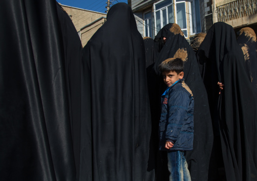 Child Standing Behind Iranian Shiite Muslim Women Covered In Mud During Ashura, The Day Of The Death Of Imam Hussein, Kurdistan Province, Bijar, Iran