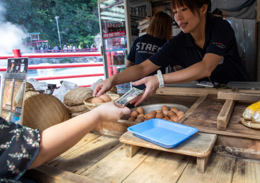 Tourist buying eggs to cook in the hot steam of Kamado jigoku cooking pot hell, Oita Prefecture, Beppu, Japan