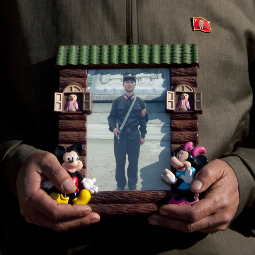 North Korean man showing his son picture serving in the army in a Mickey mouse frame, North Hamgyong Province, Jung Pyong Ri, North Korea