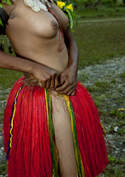 Topless woman wearing a traditional red grass skirt, Milne Bay Province, Trobriand Island, Papua New Guinea