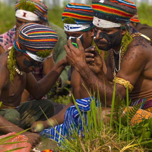 Warriors looking at themselves in mirrors before a Sing-sing ceremony, Western Highlands Province, Mount Hagen, Papua New Guinea