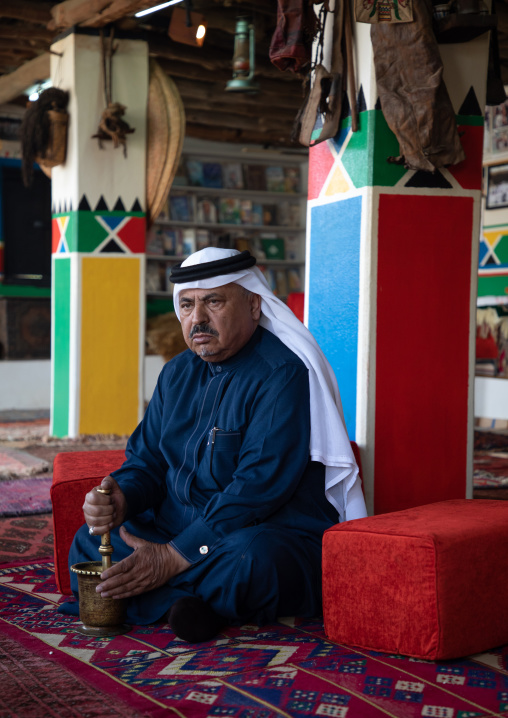 Saudi man preparing coffe with a pestle in a majlis, Asir province, Tanomah, Saudi Arabia