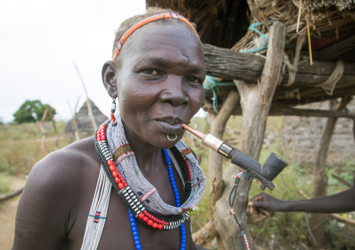 Toposa tribe woman smoking pipe in a village, Namorunyang State, Kapoeta, South Sudan