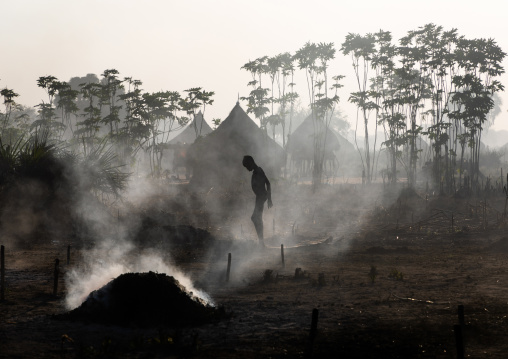 Mundari tribe boy taking care of the bonfires made with dried cow dungs to repel flies and mosquitoes, Central Equatoria, Terekeka, South Sudan